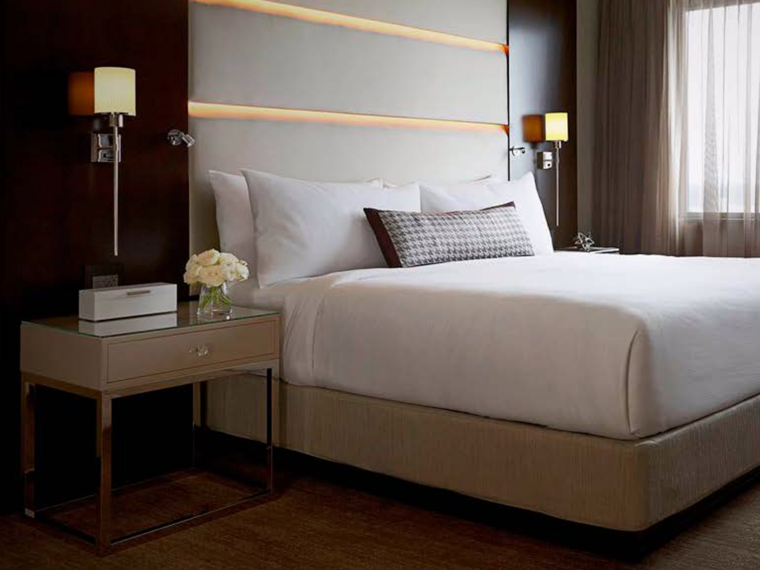 hotel bed with nightstand casegood next to it